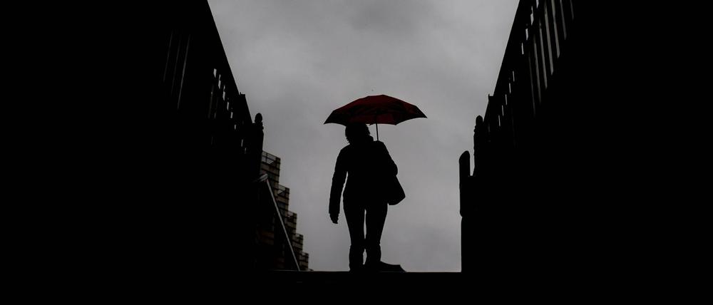 Eine Person mit Regenschirm verlässt eine U-Bahn-Station. (Symbolbild)