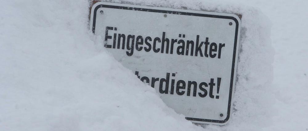 Bei eisiger Kälte auf dem Brocken steckt ein Schild mit der Aufschrift "Eingeschränkter Winterdienst" im Schnee. 