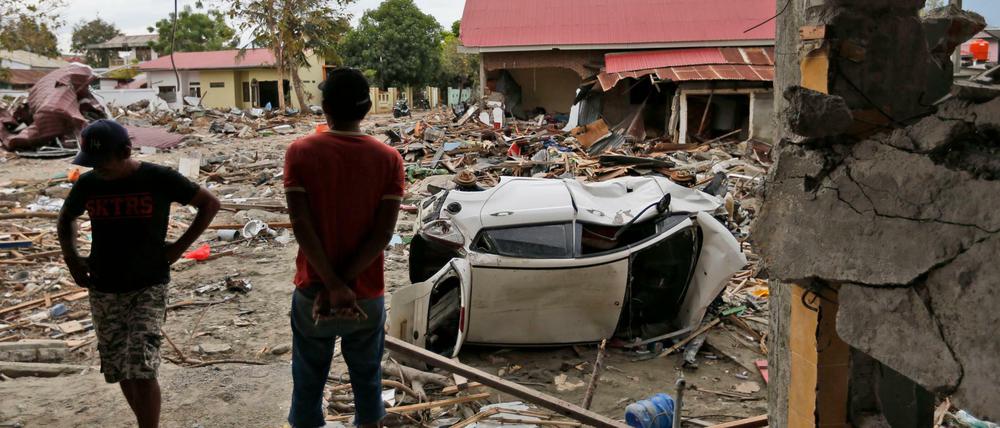 Männer betrachten die Schäden in einem vom Tsunami verwüsteten Gebiet in Palu. Ein Erdbeben hatte die Provinz Zentral-Sulawesi am 28. September 2018 erschüttert und einen Tsunami ausgelöst.
