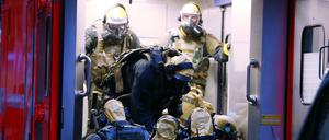 SEK-Beamte mit Atemschutzmasken und Schutzanzügen steigen in einem Krankenwagen.