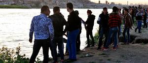 Menschen stehen am Ufer des Flusses Tigris, auf dem eine Fähre gesunken ist. 