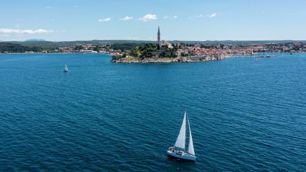 Ein Boot segelt im adriatischen Meer vor dem malerischen kroatischen Touristenort Rovinj. 