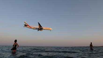 Touristen beobachten ein Boeing 777-300ER-Flugzeug von Emirates Airlines (Symbolbild)