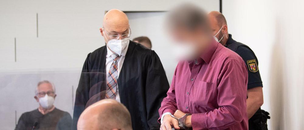 Der Angeklagte im Prozess um den Tankstellen-Mord wird in Handschellen in den Gerichtssaal gebracht.