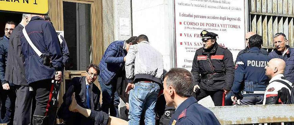 Rettungskräfte und Polizisten helfen einem Verwundeten auf dem Gerichtsgebäude in Mailand. 