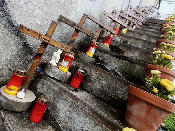 Holzkreuze und frisch gepflanzte Blumen für die Opfer.