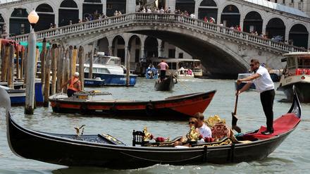 Gondeln, Boote sowie ein Vaporetto fahren auf dem Canale Grande vor der Rialtobrücke in Venedig. 