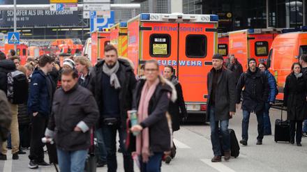 Reisende und Rettungswagen vor den Terminals des Hamburger Flughafens.