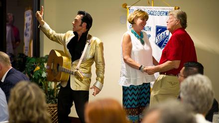 Ein Elvis-Imitator tritt auf der Bühne auf, während John Rada (r) und seine Frau Llana Smith (M) am 27.08.2015 nach ihrer erneuten Hochzeit auf einem Tourismuskongress in Las Vegas (USA) tanzen. Jährlich werden in Vegas nach Angaben der Stadt mehr als 80 000 Ehen geschlossen - das sind im Schnitt 200 pro Tag.