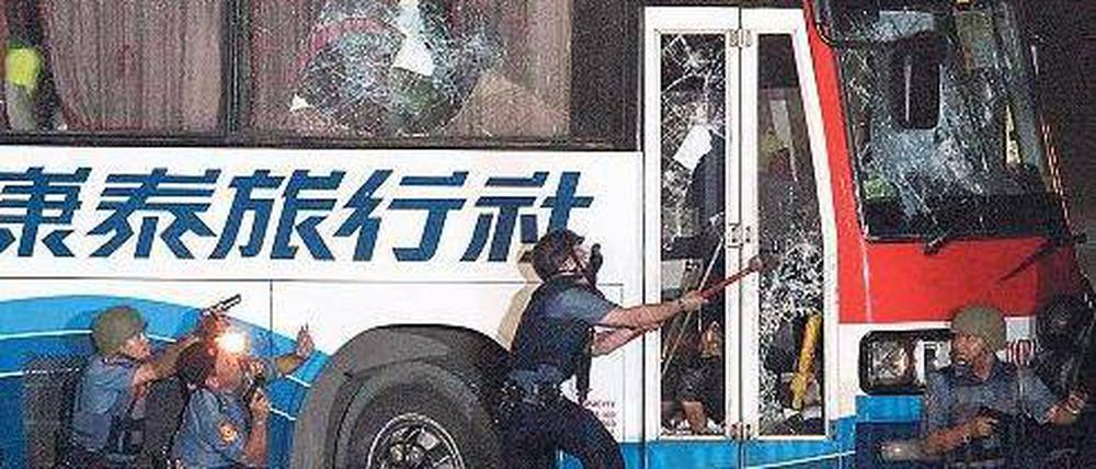 Mit Hammerschlägen versucht ein Polizist, die Tür einzuschlagen. Foto: dpa