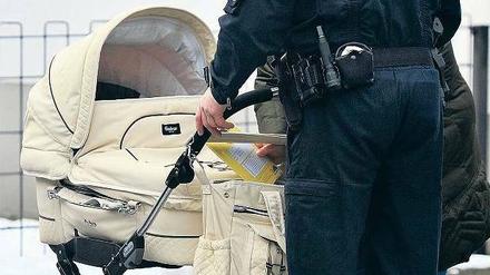 Geborenenkontrolle. Ein Polizist checkt einen verdächtigen Kinderwagen. 