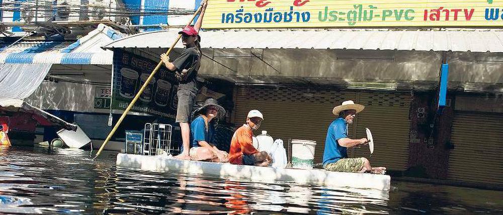 Alles was schwimmt. Die Menschen suchen sich mit improvisierten Booten ihren Weg durch die Fluten in Rangsit, an den Rändern von Bangkok. Foto: AFP