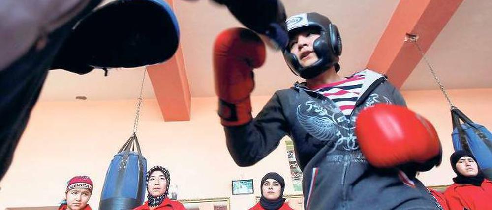 Mädchen in den Ring. Sadaf Rahimi mit ihrem Trainer in ihrem Kabuler Fitnesscenter. An der Wand stehen andere Frauen, die ebenfalls zum Boxen kommen. Foto: Omar Sobhani, Reuters