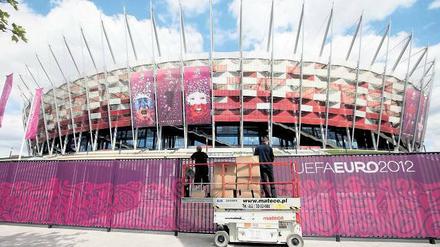 Noch zu tun. Arbeiter befestigen einen Sichtschutz am Nationalstadion in Warschau, in dem am Freitag das EM-Eröffnungsspiel Polen gegen Griechenland ausgetragen wird.