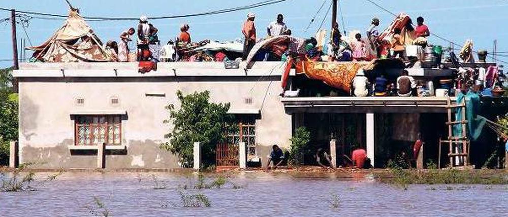 Menschen sind auf ein Hausdach geflüchtet, um den Fluten zu entkommen. 