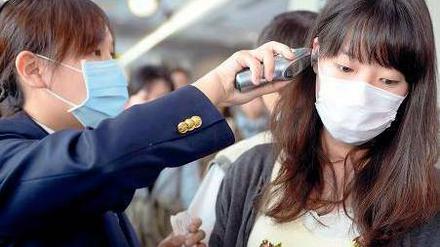 Ein Mitarbeiterin misst die Temperatur einer Reisenden auf dem Sungshan Airport in Taipei. 