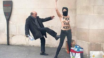 Ein Mann vor einer Moschee in Paris tritt nach einer Aktivistin, die gegen Frauen-Unterdrückung im Islam protestiert. 