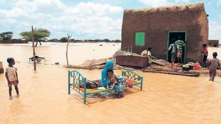 Eine Frau sitzt mit ihrem Kind in der Nähe der sudanesischen Hauptstadt Khartoum auf ihrem Bett. Ihr Haus wurde nach heftigen Regenfällen von den Fluten des Nils stark beschädigt. 