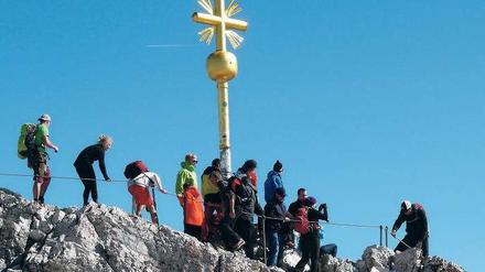 Ansturm auf die Zugspitze. Die Menschen drängeln sich am Gipfelkreuz. 