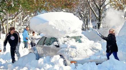 Kunst am Schnee. Diese Menschen in Hamburg, einem Vorort von Buffalo, räumen ihr Auto frei. Viele Menschen starben, weil sie von den Schneemassen eingeschlossen wurden.