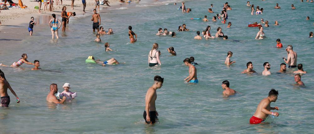Menschen baden in großer Hitze am Strand bei Magaluf.