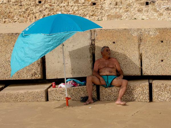 Ein Mann im spanischen Cádiz schützt sich vor der heißen Sonne.