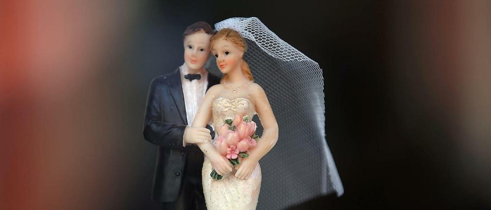 Ein Hochzeitspaar aus Wachs steht auf einer Hochzeitstorte. (Symbolbild)