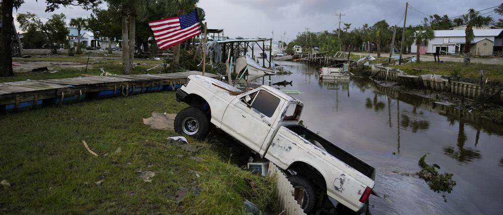 Ein Pick-up steht neben einer amerikanischen Flagge nach dem Durchzug des Hurrikans „Idalia“ auf halber Strecke in einem Kanal.