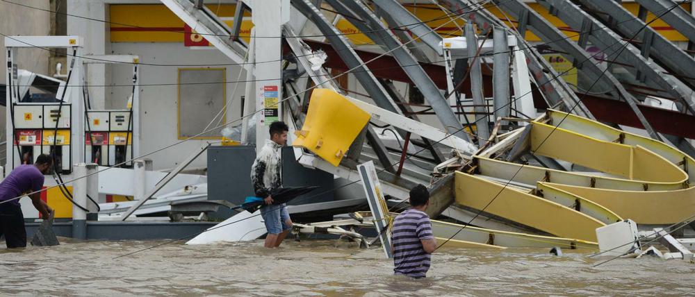 Menschen waten in Humacao, Puerto Rico durch überflutete Straßen.