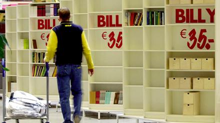 Ein Mitarbeiter des schwedischen Möbelkonzerns IKEA schiebt einen Einkaufswagen an dem Allround-Regal "Billy" vorbei. (Archivbild)