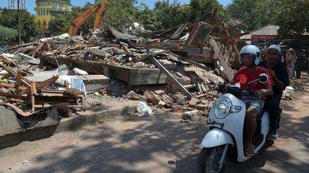Ein Roller fährt an den Trümmern eines Hauses vorbei, das bei einem Erdbeben eingestürzt ist.