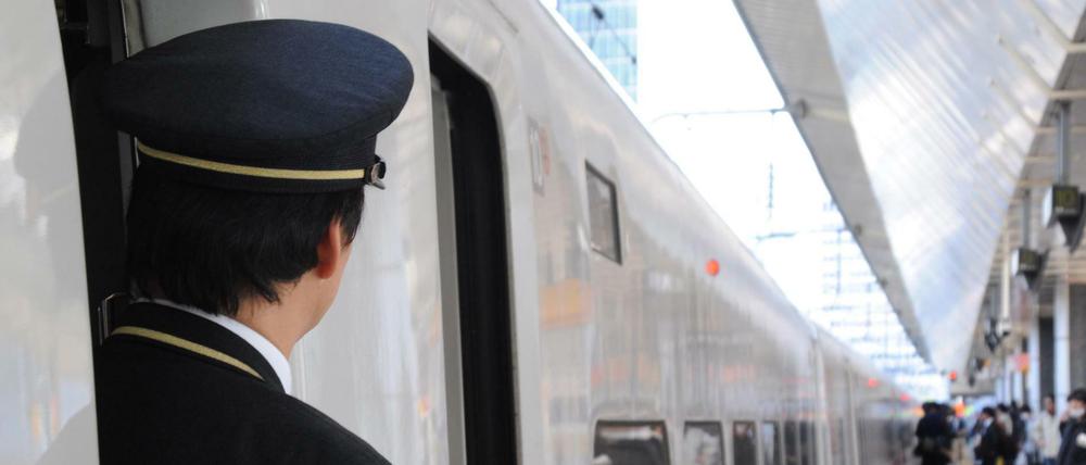 Ein Zugbegleiter schaut aus der Tür eines Hochgeschwindigkeitszugs Shinkansen. 