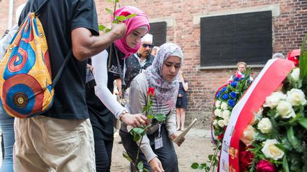 Junge Muslimas legen Blumen an der sogenannten Todesmauer im ehemaligen deutschen Konzentrationslager Auschwitz nieder.