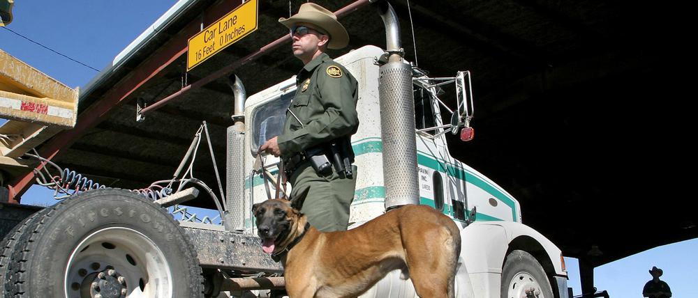 Ein US-Grenzbeamter sucht mit einem Drogenspürhund nach illegaler Fracht.