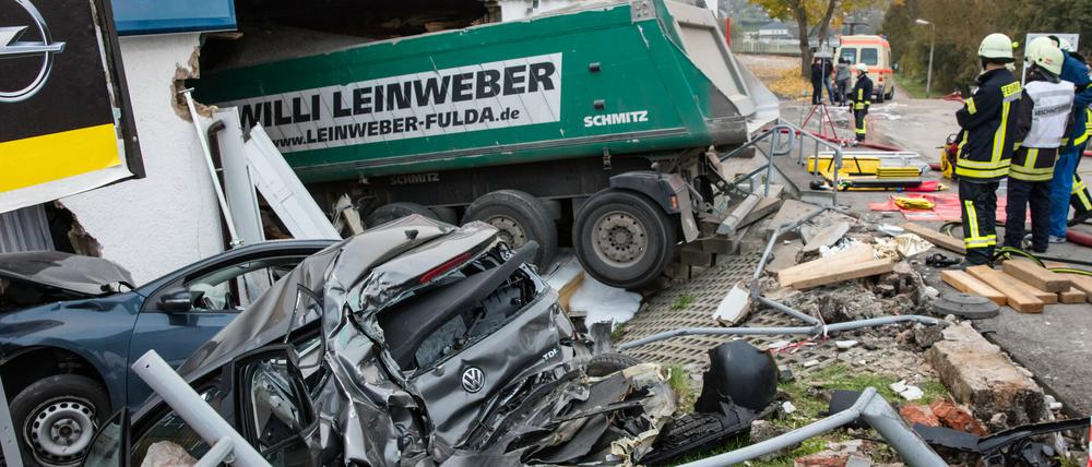 Mitarbeiter von Feuerwehr und Technischem Hilfswerk stehen am 13.10.2015 an einem Autohaus in Meiningen (Thüringen), nachdem ein LKW bei einem Unfall in das Autohaus gefahren war und dabei weitere Fahrzeuge beschädigt hatte.