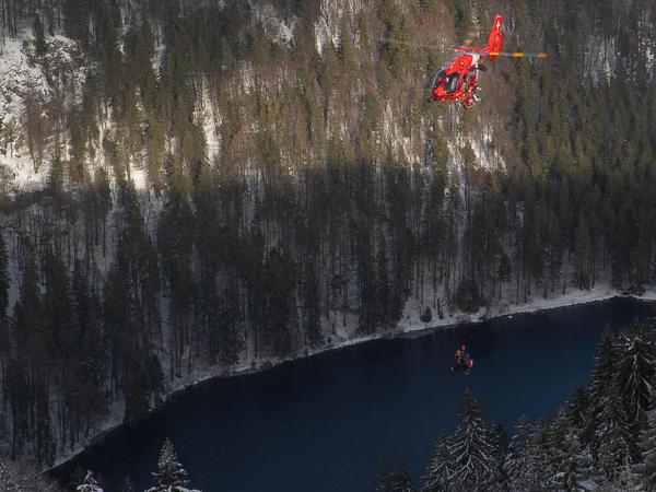 Ein Rettungshubschrauber fliegt mit einem bei einer Lawine verunglückten Mann und einem Luftretter der Bergwacht Schwarzwald über den Feldsee am Feldberg. 