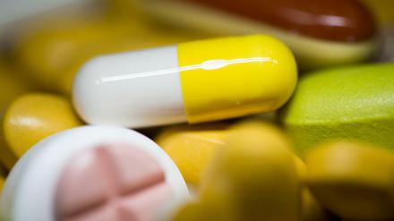 Tabletten, Kapseln und Pillen in verschiedenen Farben liegen in einem Medikamenten-Behälter einer Apotheke. 