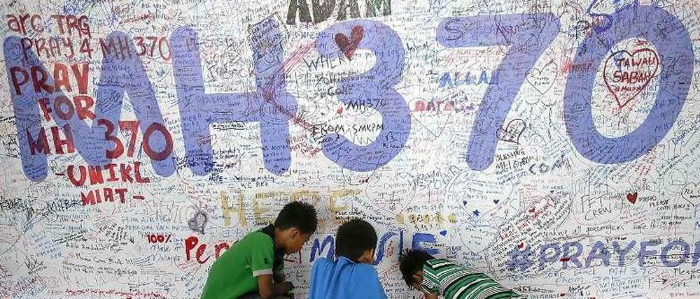 Kinder in Kuala Lumpur, Malaysia, vor einer Wand mit aufgemalten Bekundungen der Hoffnung für die Insassen des verschollenen Flugs MH370.