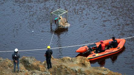 Ein Taucher wird in einem Baggersee unter Wasser gelassen, um dort nach weiteren Leichenteilen zu suchen. 
