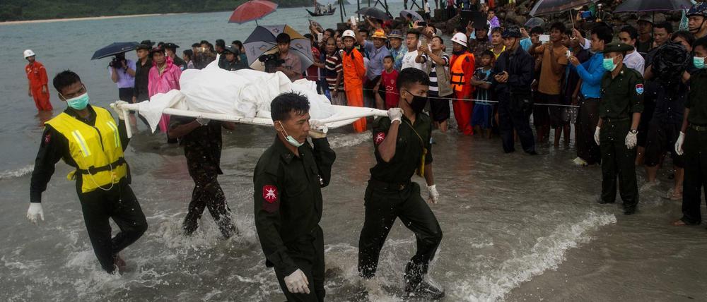 Militärangehörige von Myanmar bergen nahe des Ortes Sanhlan auf einer Trage eines der Opfer des Flugzeugunglücks. 