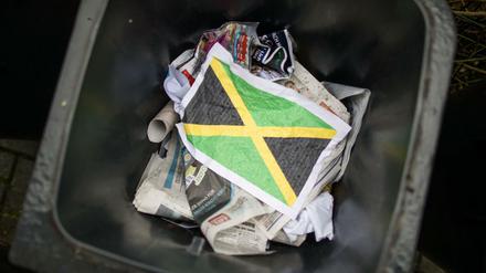 Ein zerknittertes Blatt Papier mit einer aufgedruckten Jamaika-Fahne im Müll (gestellte Szene)