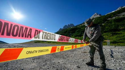 Ein Beamter der italienischen Finanzpolizei blockiert den Zugang zum Marmolada-Berg und zum Punta-Rocca-Gletscher in den italienischen Alpen mit Absperrband. 