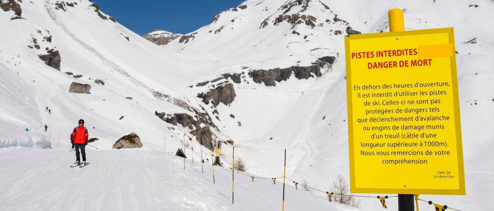 Ein Skifahrer fährt an einem Warnschild vorbei, welches nahe an der Stelle steht, an welcher eine Lawine abgegangen ist.