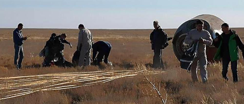 Rettungsmannschaften stehen neben der notgelandeten russischen Sojus-Kapsel in der Steppe von Kasachstan.