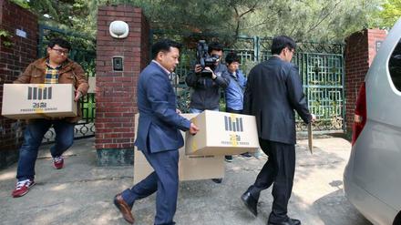 Ermittler tragen Kisten mit Akten aus einem Büro in Seoul.
