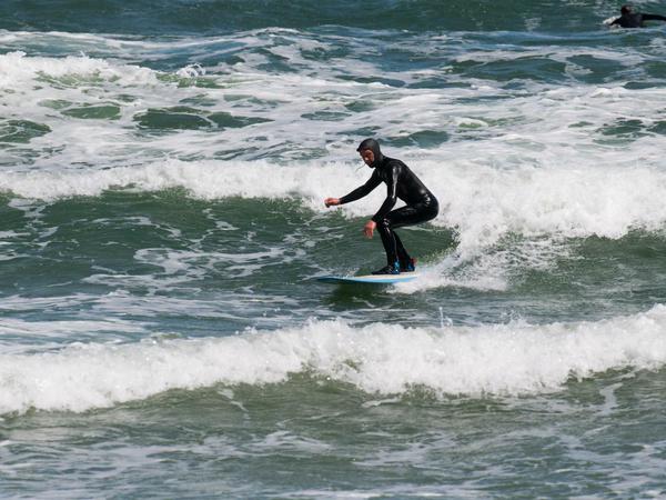 Nils Miller springt mit seinem Surfbrett über Wellen in der Ostsee bei Binz.