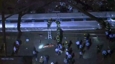 Rettungskräfte versuchen Passagiere aus einem umgestürzten Waggon zu retten. 