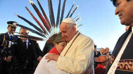 Papst Franziskus umarmt einen Jungen bei seiner Ankunft in Bolivien. Rechts im Bild: Präsident Evo Morales. 