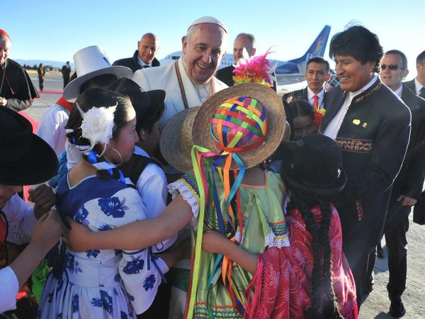 Papst Franziskus wird bei seiner Ankunft in Bolivien von Präsident Evo Morales (r) und einigen traditionell gekleideten Kindern empfangen. 