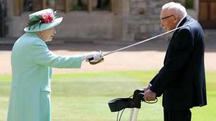 Königin Elizabeth II. (l) schlägt Sir Tom Moore (r), Weltkriegsveteran und Rekord-Spendensammler, auf Schloss Windsor zum Ritter.